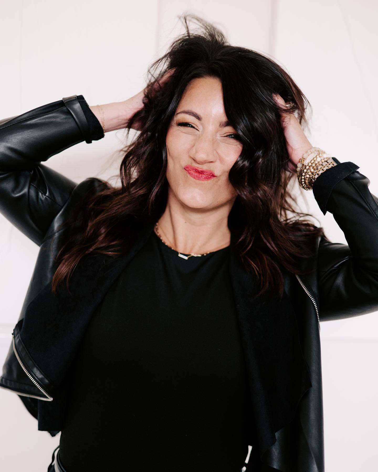 girl with dark hair with hands in her hair messing up hair